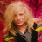 Pixelated image of a person with long blonde hair wearing dark clothing against a red and pink background.