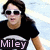 Pixelated image of a person with long dark hair wearing white-framed sunglasses and a black T-shirt with 'Miley' text, set against a light blue and white background.