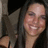 A pixelated close-up of a person with long dark hair smiling, wearing a light-colored top against a dark background.