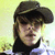 Pixelated close-up of a person wearing a dark cap and high-collared dark clothing against a light yellow background.