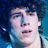Pixelated close-up of a person with dark curly hair against blue background, showing subtle facial expression changes between frames.