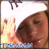 A person wearing a white cap with dark text, holding their hand near the face in a blurred motion, with blue stylized text at the bottom.