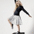A woman in a black long-sleeve top and silver checkered skirt performs dynamic poses against a white background, with one pose showing her standing on a black cube.
