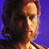 Pixelated static image of a person's face in profile against blue background with warm lighting and dark hair.
