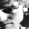 Black-and-white animated sequence showing a person's face with shifting white geometric shapes over the eyes and mouth, accompanied by small square elements scattered across the frame.