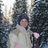 Pixelated static image of a person with dark hair wearing light-colored clothing holding an object against a blurred background.