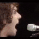 Animated contact sheet of a person with curly brown hair in five distinct poses and settings including stage performance, close-up facial expressions, and casual outdoor shots.