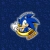 Pixelated circular icon with blue background, featuring a stylized character's face in yellow and white tones.