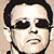 Pixelated static icon of a person with dark hair and sunglasses against a light background.