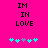 A bright pink background displays black pixelated text reading "IM IN LOVE" above five cyan and gray pixelated heart shapes, with the hearts' arrangement changing between frames.