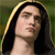Pixelated portrait of a person with long dark hair and a light-colored hooded garment against a greenish background.