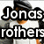 Pixelated image of four people in white and gray clothing with text overlay reading "Jonas brothers UCK!!!!!" on a light background.