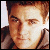 Pixelated close-up of a person's face with light brown hair, wearing a dark jacket over a light shirt, against a light background.