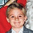 Pixelated image of a person with light brown hair wearing a white shirt and dark jacket, red background on left side, static composition.