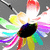 A colorful, multi-petaled flower-like icon with a black center, red and white top petals, and rainbow-colored lower petals, displayed in a