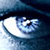 Pixelated close-up of a human eye with blue and white tones, featuring visible eyelashes and a dark pupil against a gradient background.