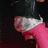 A person in a black top with white trim and pink sleeves is shown from the shoulders down, with a dark background.