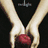 Two hands hold a red apple against black background with white text above; chess pieces on reflective surface below.
