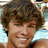 A pixelated image shows a person with brown curly hair on the left, next to a bright cyan background with two lines of black pixelated text reading HOTTIE HOTTIE.
