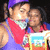 Two figures in purple and red clothing hold a book with 'TNT' text, one figure's face partially obscured by another.