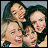 Four people with dark hair pose closely together in a pixelated static image, their faces and upper bodies visible against a light background.