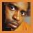 Pixelated close-up of a person's face with brown eyes, dark eyebrows, and an orange shirt against a black and gray background.