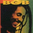Pixelated image of a person with long dark hair holding a microphone, set against a dark background with a yellow banner at the top.