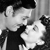 Black-and-white pixelated image of two figures in close physical proximity with one figure's hand near the other's face.