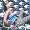 A woman in a blue dress with red accents reclines against a patterned background of repeated blue and white shapes.