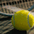 Two yellow tennis balls on a textured surface with orange text reading 'Lady', 'Warrior', and 'Tennis' appearing sequentially.