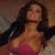 Pixelated image of a person with long dark hair wearing a black jacket over a pink top against a blurred background.