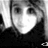 Black-and-white pixelated image of a person with dark hair, wearing a dark top, holding an object near their face.