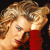 A pixelated close-up of a person with light brown curly hair wearing a red garment against a dark background.