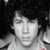 Black-and-white image of a person with dark curly hair wearing a light-colored shirt, displayed in a