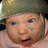 A baby wearing a green helmet and light pink clothing with subtle blue eyes, mouth slightly open in three