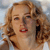 Pixelated close-up of a person with light brown curly hair, red lips, and closed eyes against a light blue background.