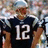 A person wearing a dark blue jersey with white number 12, silver helmet, and shoulder pads stands against a blurred background.