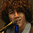 Four- of a person with curly hair singing into microphones, overlaid with blue text reading I LOVE THE JONAS BROTHERS