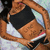 Pixelated static image of a figure with brown hair, black top, and white accents, holding a black object against a light background.