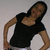 A person in a black short-sleeve top and light-colored pants poses with hands on hips against a plain background, shown
