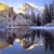 Pixelated landscape with mountains, trees, and a reflective body of water under a light blue sky.