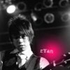 A black-and-white photo of a person with short hair wearing a dark jacket, with a red light and text 'CYAN' in the background.