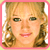 Pixelated close-up of a person with light brown hair styled in loose curls, wearing dark eyeshadow and pink lipstick against a white background.