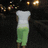 A pixelated figure in a white top and green skirt stands against a dark background with scattered light spots.