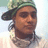 Pixelated portrait of a person wearing a green cap and light-colored shirt against a pale background.