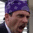 A pixelated image of a person wearing a purple bandana and dark clothing against a bright green background with pink text.