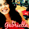 A smiling woman with dark hair holds a yellow and red object while wearing a red top with 'Gabriella' text in white script.