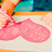 Pixelated image of a character's lower body wearing pink pants and orange shoes, with teal and dark blue background elements.