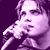 Pixelated purple-toned static image of a person singing into a microphone with visible facial features and hair details against a solid dark background.