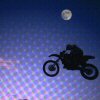 Silhouette of a motorcyclist riding a dirt bike against a gradient night sky with a full moon and pixelated light effects.